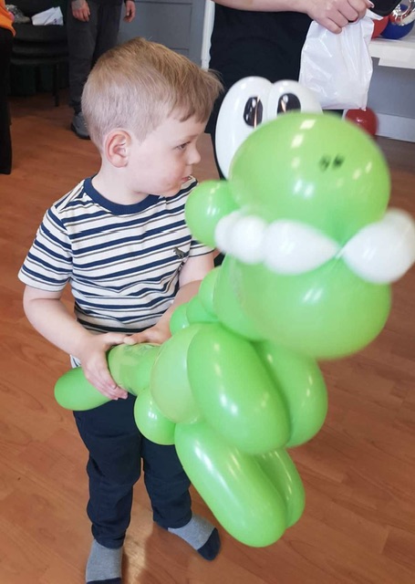 Boy holding a dinosaur balloon at a party in Telford